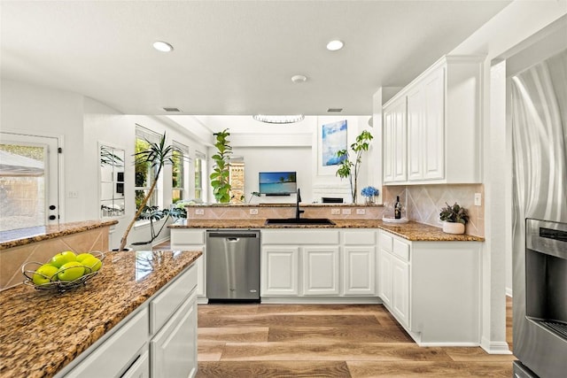 220 Grafton Ln, Austin, TX 78737 - kitchen featuring appliances with stainless steel finishes, a sink, light wood-type flooring, tasteful backsplash, and recessed lighting