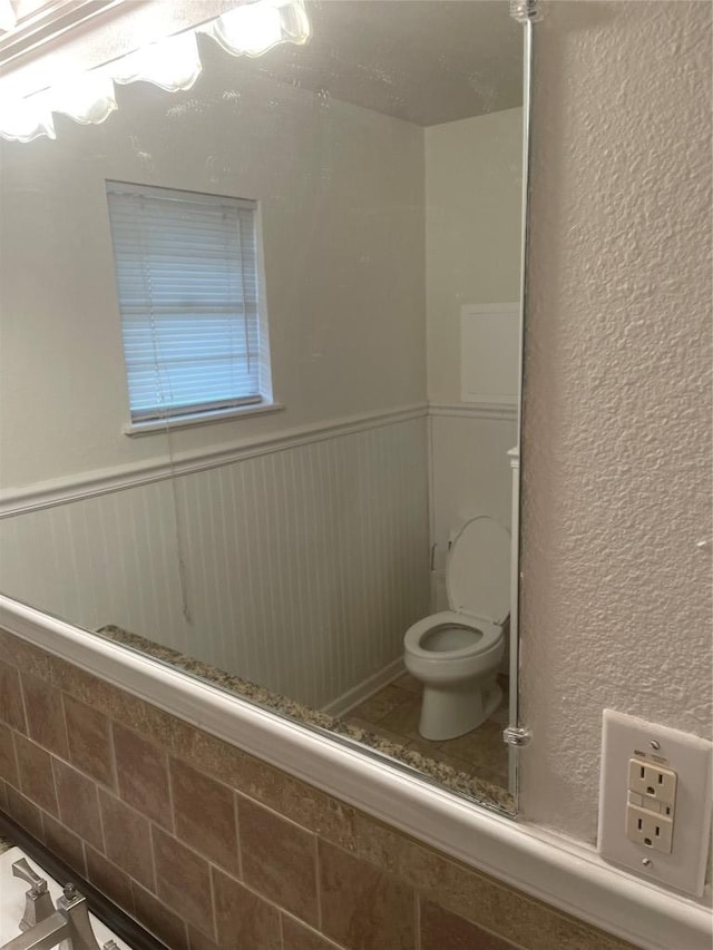 207 N 1st St, Thorndale, TX 76577 - bathroom featuring toilet and a wainscoted wall