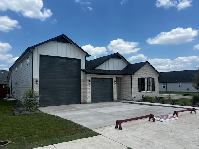 20408 Stelfox St, Manor, TX 78653 - view of front of property featuring board and batten siding, a garage, concrete driveway, and brick siding