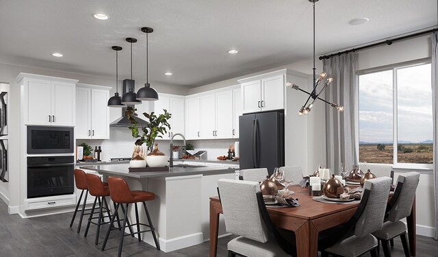 20408 Stelfox St, Manor, TX 78653 - kitchen with black appliances, plenty of natural light, dark wood-style flooring, a kitchen island with sink, and recessed lighting