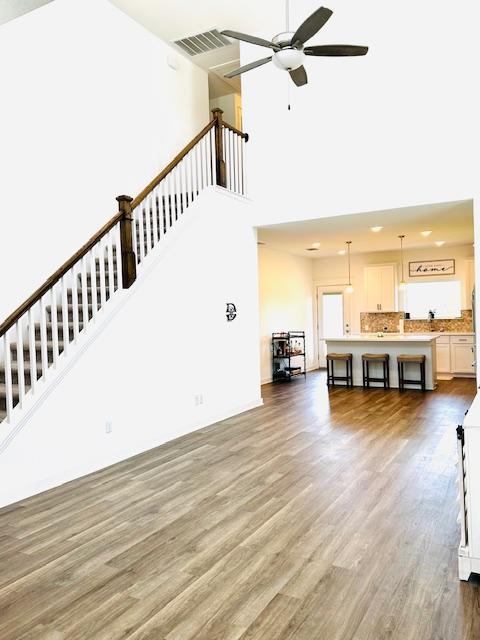 2376 Sawdust Dr, Georgetown, TX 78633 - unfurnished living room with a towering ceiling, wood finished floors, a ceiling fan, and stairway