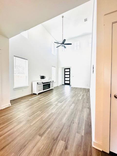 2376 Sawdust Dr, Georgetown, TX 78633 - unfurnished living room with wood finished floors, ceiling fan, a high ceiling, and baseboards