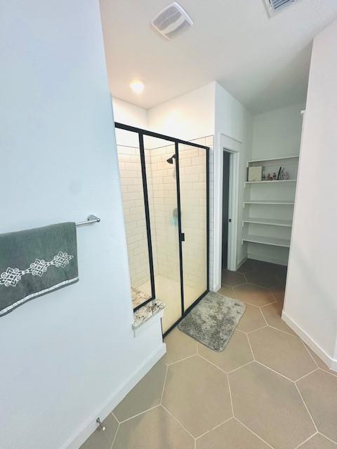 2376 Sawdust Dr, Georgetown, TX 78633 - bathroom with a stall shower, baseboards, tile patterned flooring, and a spacious closet