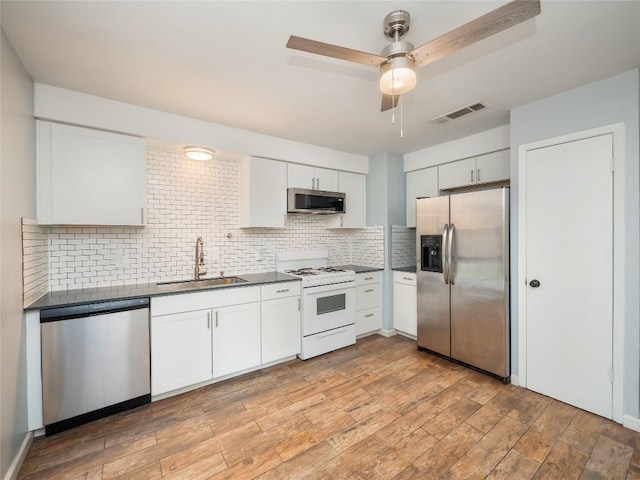 410 Blueberry Hl, Austin, TX 78745 - kitchen featuring stainless steel appliances, dark countertops, white cabinets, and tasteful backsplash