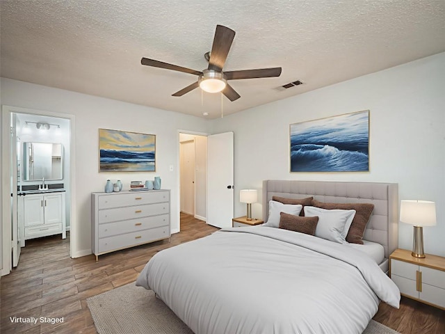 410 Blueberry Hl, Austin, TX 78745 - bedroom featuring a textured ceiling, wood finished floors, connected bathroom, and ceiling fan