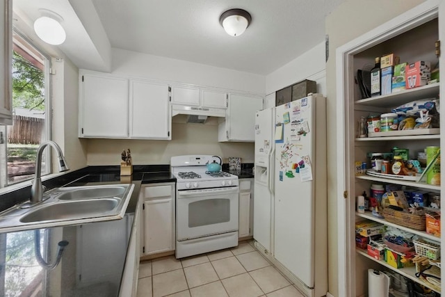 4802 Peach Grove Ct, Austin, TX 78744 - kitchen with white appliances, a sink, under cabinet range hood, dark countertops, and light tile patterned floors