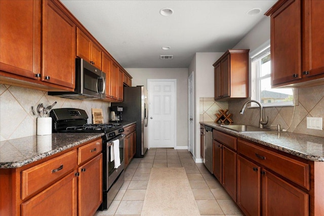 228 Wallops, Kyle, TX 78640 - kitchen with appliances with stainless steel finishes, a sink, backsplash, baseboards, and dark stone countertops
