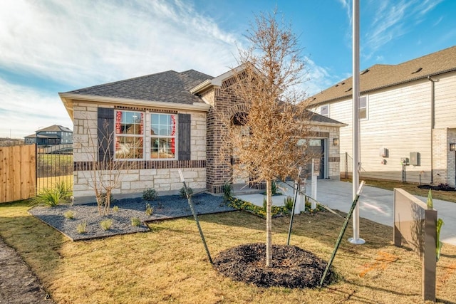 17112 Vernal Rd, Manor, TX 78653 - view of front facade featuring stone siding, roof with shingles, an attached garage, and concrete driveway