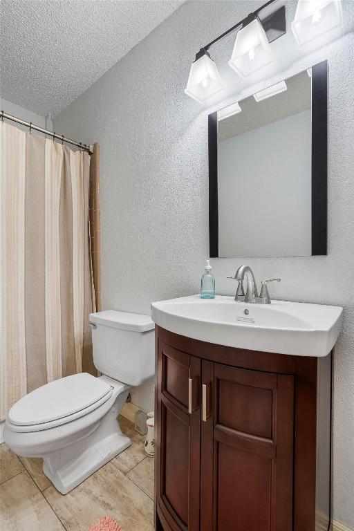 2201 Carolyn Dr, Taylor, TX 76574 - full bathroom featuring a textured wall, vanity, a textured ceiling, tile patterned floors, and curtained shower