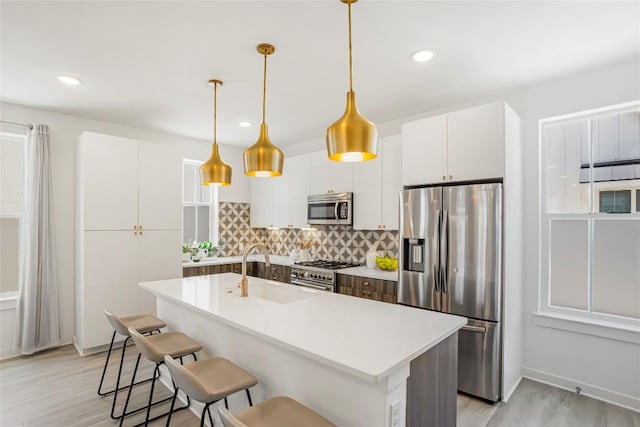 2624 Metcalfe Rd Unit 17, Austin, TX 78741 - kitchen with appliances with stainless steel finishes, a sink, decorative backsplash, light wood-style floors, and white cabinets