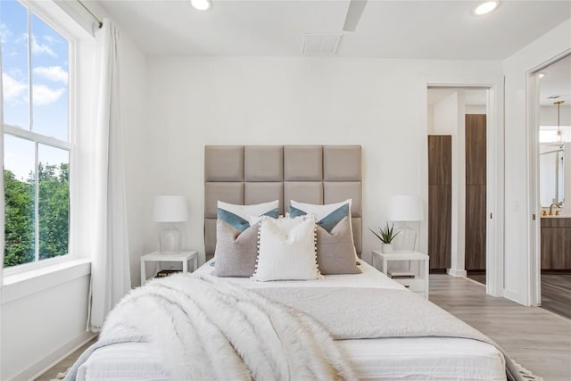 2624 Metcalfe Rd Unit 17, Austin, TX 78741 - bedroom featuring recessed lighting, wood finished floors, baseboards, connected bathroom, and a sink