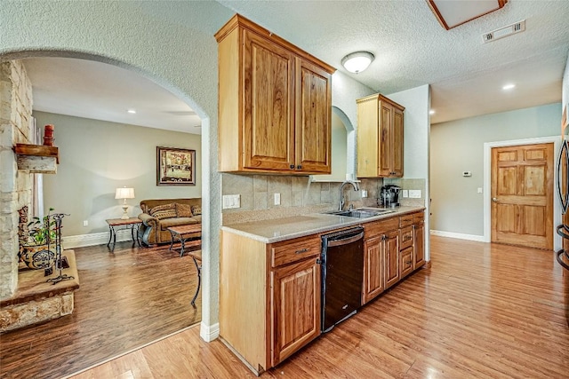 106 Masonic Lodge Rd, Wimberley, TX 78676 - kitchen with black dishwasher, light wood-type flooring, a sink, light countertops, and baseboards