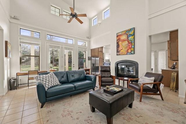 9300 N Madrone Trl, Austin, TX 78737 - living area featuring ceiling fan, a high ceiling, light tile patterned floors, a glass covered fireplace, and french doors