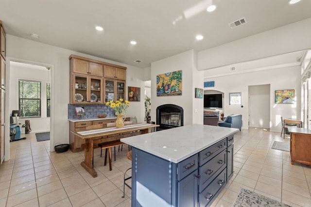 9300 N Madrone Trl, Austin, TX 78737 - kitchen with light tile patterned floors, recessed lighting, decorative backsplash, a center island, and a fireplace