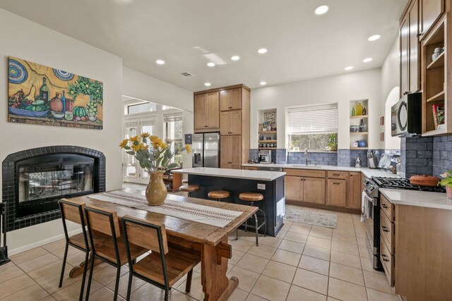 9300 N Madrone Trl, Austin, TX 78737 - kitchen with open shelves, a fireplace, stainless steel appliances, light countertops, and decorative backsplash