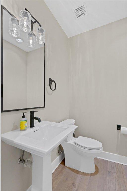 1405 Parkinson Dr, Austin, TX 78704 - half bath featuring toilet, wood finished floors, vaulted ceiling, and baseboards