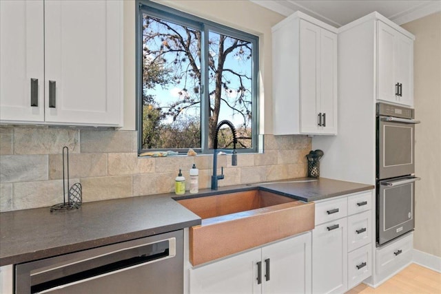 1405 Parkinson Dr, Austin, TX 78704 - kitchen with a sink, appliances with stainless steel finishes, dark countertops, white cabinets, and decorative backsplash