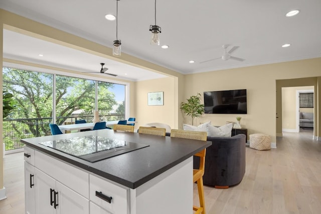 1405 Parkinson Dr, Austin, TX 78704 - kitchen with ceiling fan, black electric cooktop, dark countertops, light wood-style floors, and crown molding