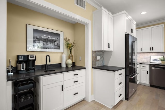 1405 Parkinson Dr, Austin, TX 78704 - kitchen featuring stainless steel appliances, light wood-style flooring, white cabinets, dark countertops, and recessed lighting