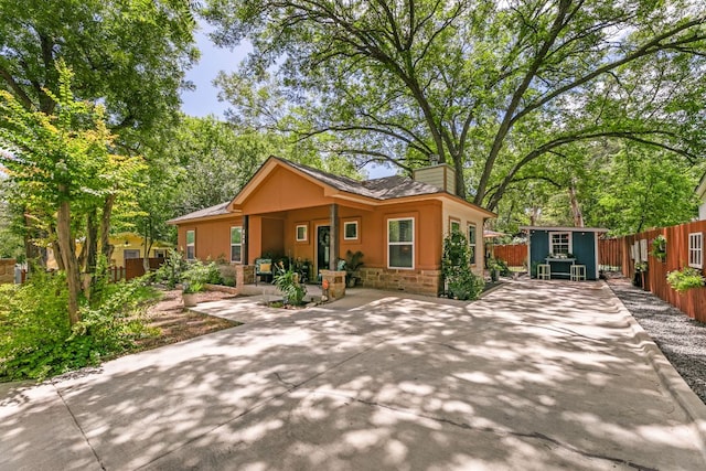 810 Monterrey St, Lockhart, TX 78644 - view of front of house featuring stone siding, a chimney, a fenced backyard, and a patio area