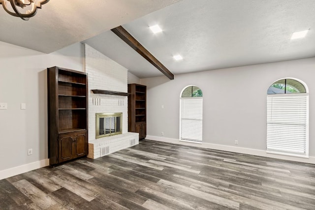 220 E Belton Ave, Rockdale, TX 76567 - unfurnished living room with dark wood finished floors, baseboards, plenty of natural light, a fireplace, and a textured ceiling
