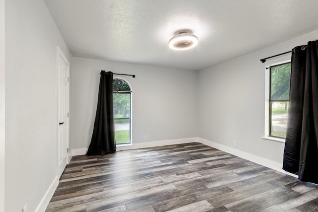 220 E Belton Ave, Rockdale, TX 76567 - unfurnished room featuring dark wood finished floors, plenty of natural light, baseboards, and a textured ceiling