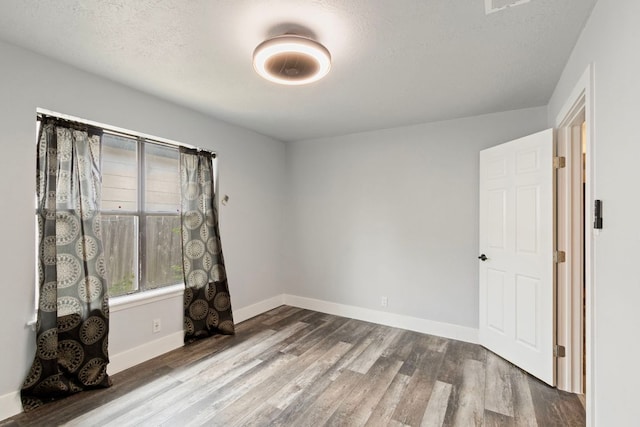 220 E Belton Ave, Rockdale, TX 76567 - unfurnished room with wood finished floors, baseboards, and a textured ceiling