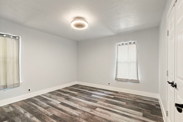 220 E Belton Ave, Rockdale, TX 76567 - unfurnished bedroom with a textured ceiling, dark wood-style flooring, and baseboards