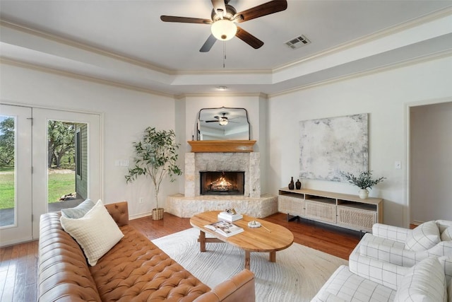 14717 Crosscreek Dr, Austin, TX 78737 - living room with a ceiling fan, hardwood / wood-style floors, a raised ceiling, crown molding, and a stone fireplace