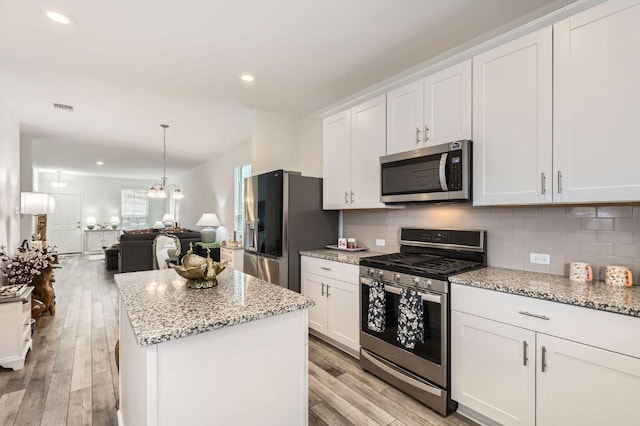 1521 W Kerr Pass, Leander, TX 78641 - kitchen featuring appliances with stainless steel finishes, tasteful backsplash, a center island, light wood-style floors, and recessed lighting