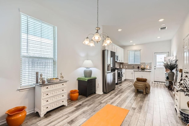 1521 W Kerr Pass, Leander, TX 78641 - kitchen featuring stainless steel appliances, a chandelier, light wood-style floors, white cabinets, and hanging light fixtures