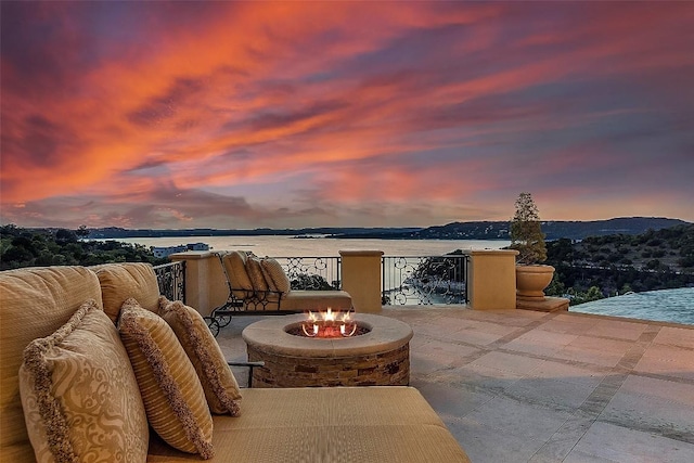 12821 Park Dr, Austin, TX 78732 - patio terrace at dusk with a fire pit, a patio, and a water view