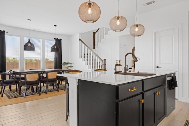 400 Turnbuckle Bnd, Leander, TX 78641 - kitchen with light countertops, light wood-style floors, dark cabinets, pendant lighting, and a center island with sink