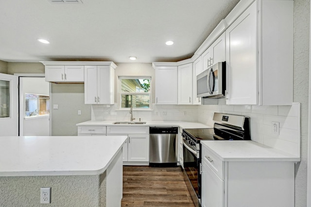 212 Walnut Ave, Luling, TX 78648 - kitchen with appliances with stainless steel finishes, dark wood-type flooring, white cabinetry, backsplash, and light countertops