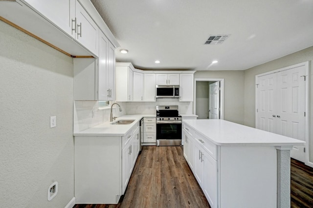 212 Walnut Ave, Luling, TX 78648 - kitchen featuring stainless steel appliances, tasteful backsplash, a kitchen island, light countertops, and white cabinetry