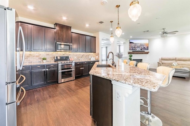 1224 Euless Ln, Leander, TX 78641 - kitchen featuring stainless steel appliances, a kitchen bar, open floor plan, dark wood-style flooring, and ceiling fan
