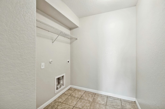121 Talon Dr, Luling, TX 78648 - laundry area featuring hookup for an electric dryer, a textured wall, light tile patterned floors, and baseboards