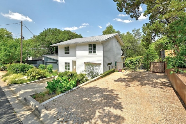 1700 S 6th St, Austin, TX 78704 - view of side of property with driveway, an attached garage, metal roof, and a standing seam roof