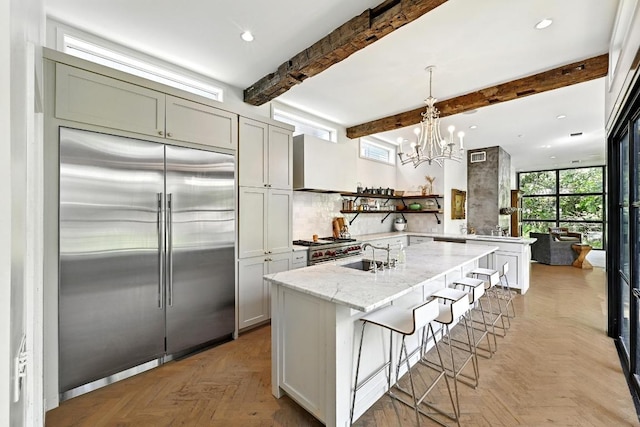 1700 S 6th St, Austin, TX 78704 - kitchen featuring high quality appliances, premium range hood, light stone countertops, a chandelier, and beamed ceiling