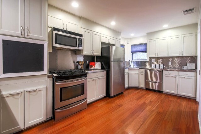 1005 Salem Ln, Austin, TX 78753 - kitchen featuring stainless steel appliances, wood finished floors, decorative backsplash, recessed lighting, and stainless steel countertops
