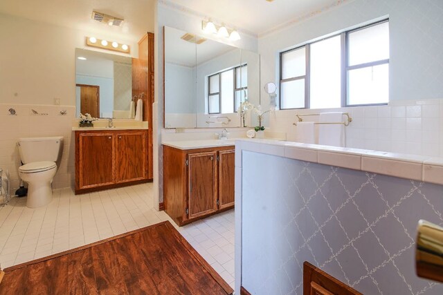1005 Salem Ln, Austin, TX 78753 - full bathroom with tile walls, two vanities, toilet, wainscoting, and tile patterned floors