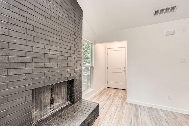 7103 Treasure Cv Unit B, Austin, TX 78745 - unfurnished living room with light wood-type flooring, a brick fireplace, and vaulted ceiling