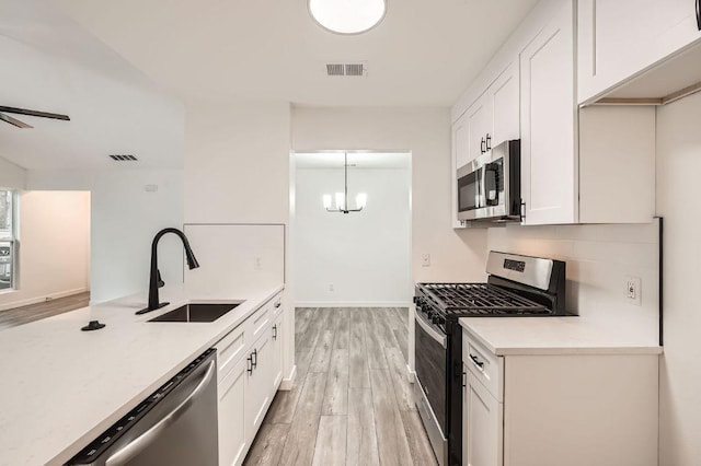7103 Treasure Cv Unit B, Austin, TX 78745 - kitchen with appliances with stainless steel finishes, light wood-style flooring, light countertops, and white cabinets