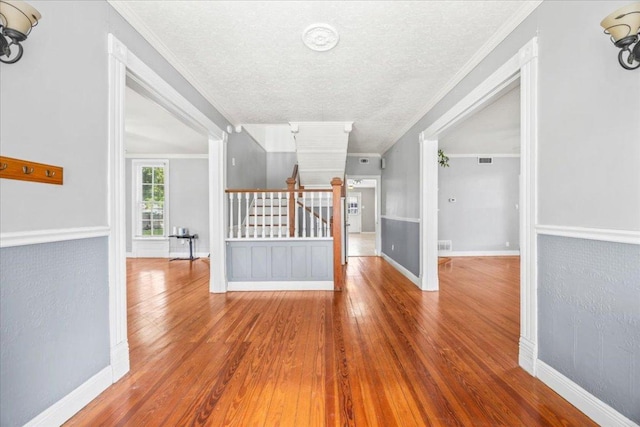 1223 Cecelia St, Taylor, TX 76574 - empty room with stairway, hardwood / wood-style floors, a textured ceiling, baseboards, and crown molding