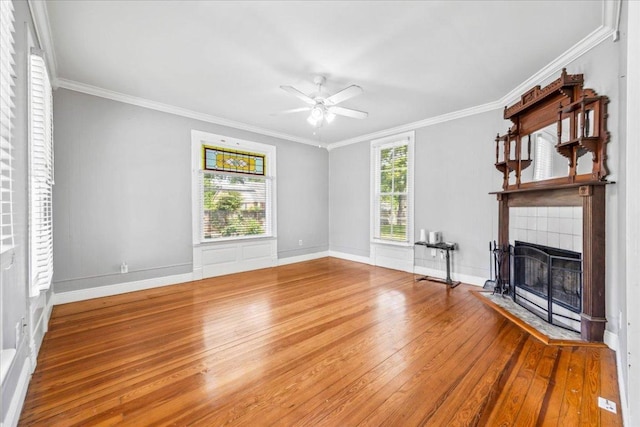 1223 Cecelia St, Taylor, TX 76574 - unfurnished living room featuring wood-type flooring, a ceiling fan, crown molding, a tiled fireplace, and baseboards
