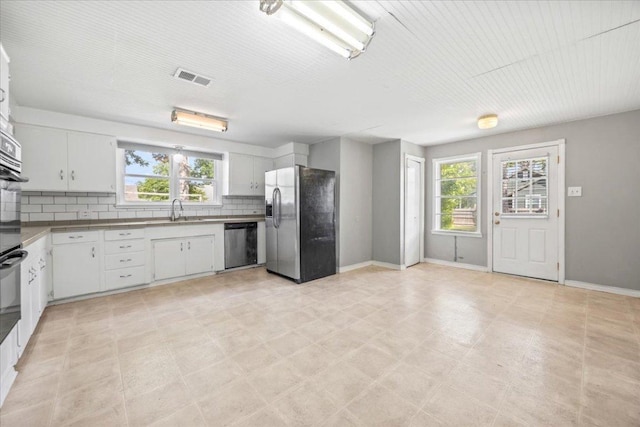 1223 Cecelia St, Taylor, TX 76574 - kitchen featuring stainless steel appliances, healthy amount of natural light, decorative backsplash, and white cabinetry