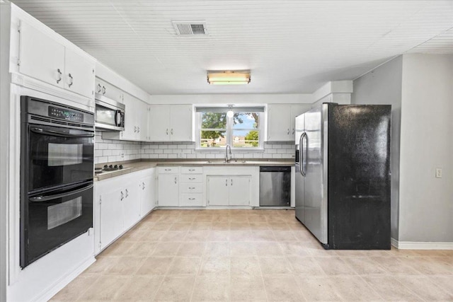 1223 Cecelia St, Taylor, TX 76574 - kitchen featuring appliances with stainless steel finishes, a sink, decorative backsplash, white cabinets, and baseboards
