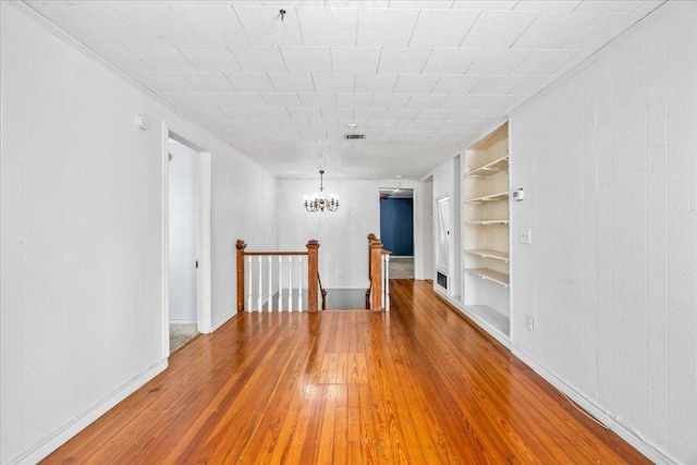 1223 Cecelia St, Taylor, TX 76574 - empty room with built in shelves, hardwood / wood-style flooring, a chandelier, and ornamental molding