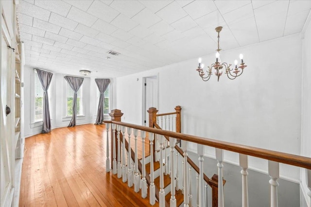 1223 Cecelia St, Taylor, TX 76574 - hallway with a chandelier, light wood-style flooring, and an upstairs landing