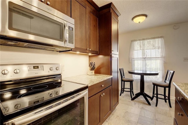 910 Duncan Ln Unit 60, Austin, TX 78705 - kitchen with appliances with stainless steel finishes, brown cabinets, and light stone countertops